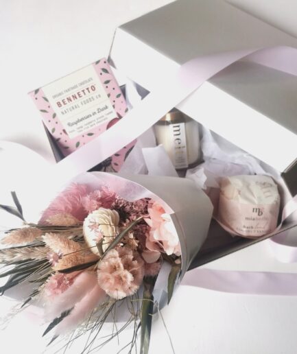 A-small-pink-bouquet-coming-out-of-a-gift-box-with-other-gifts-like-chocolate-bathbomb-and-candle