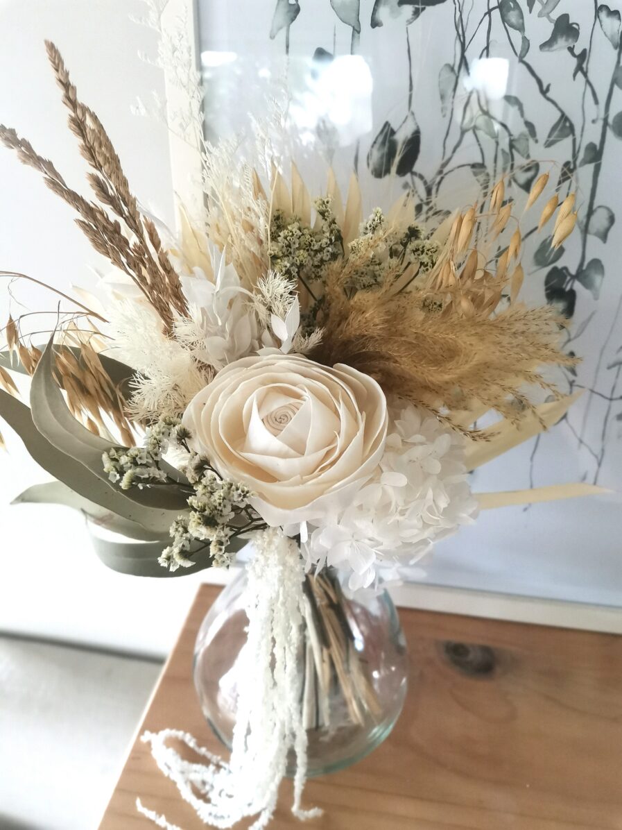 natural-and-white-dried-flowers-in-a-bouquet-are-in-a-glass-bulb-shaped-vase